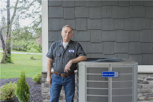 hvac technician standing next to an air conditioning unit